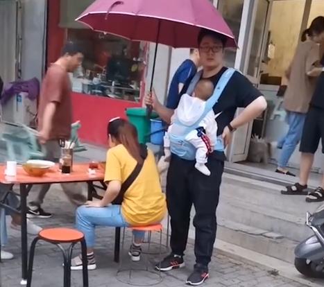 妻子雨中吃面丈夫身旁打伞 看那个老公的面相就感觉是个好老公！