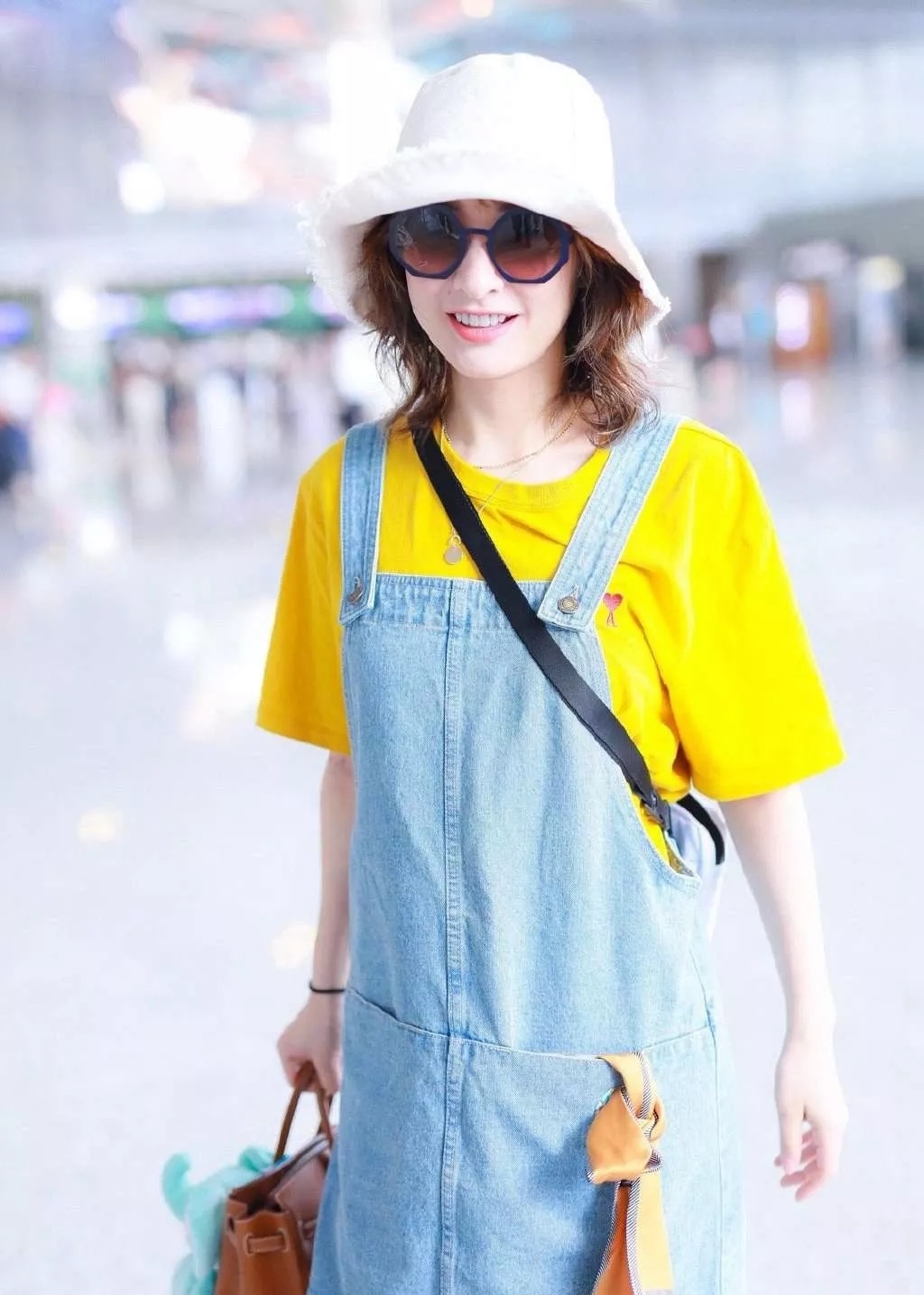 吴昕机场街拍照，黄T背带裙尽显纤细身材，头戴渔夫帽青春气息足