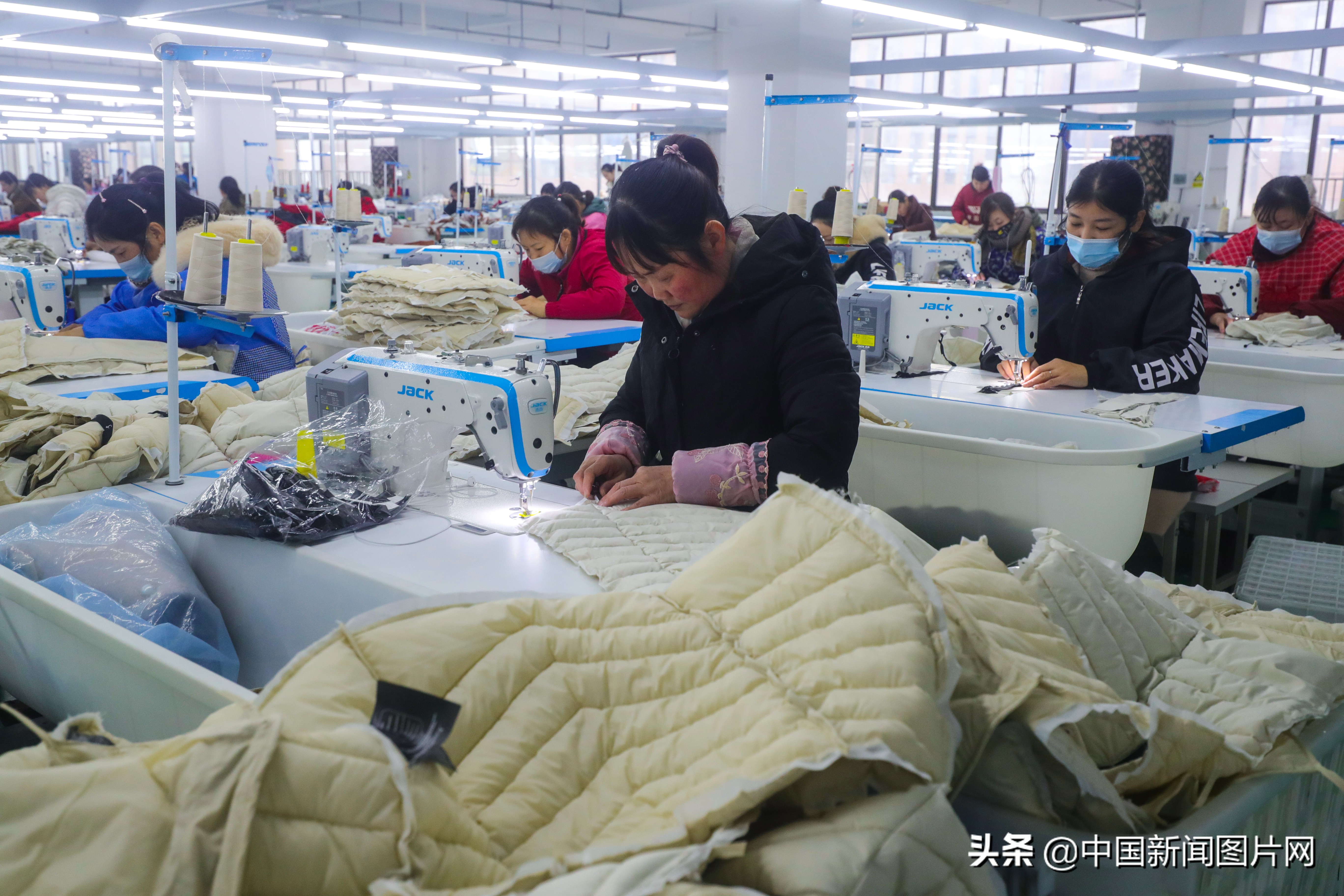 市光山县产业集聚区的良友服饰扶贫车间里工人正在赶做客户订单羽绒服