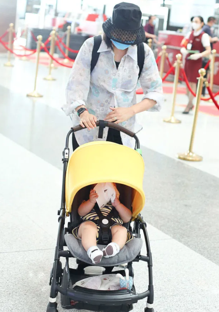 朱丹带一双儿女赶飞机，不时低头看孩子，却不见丈夫周一围的身影