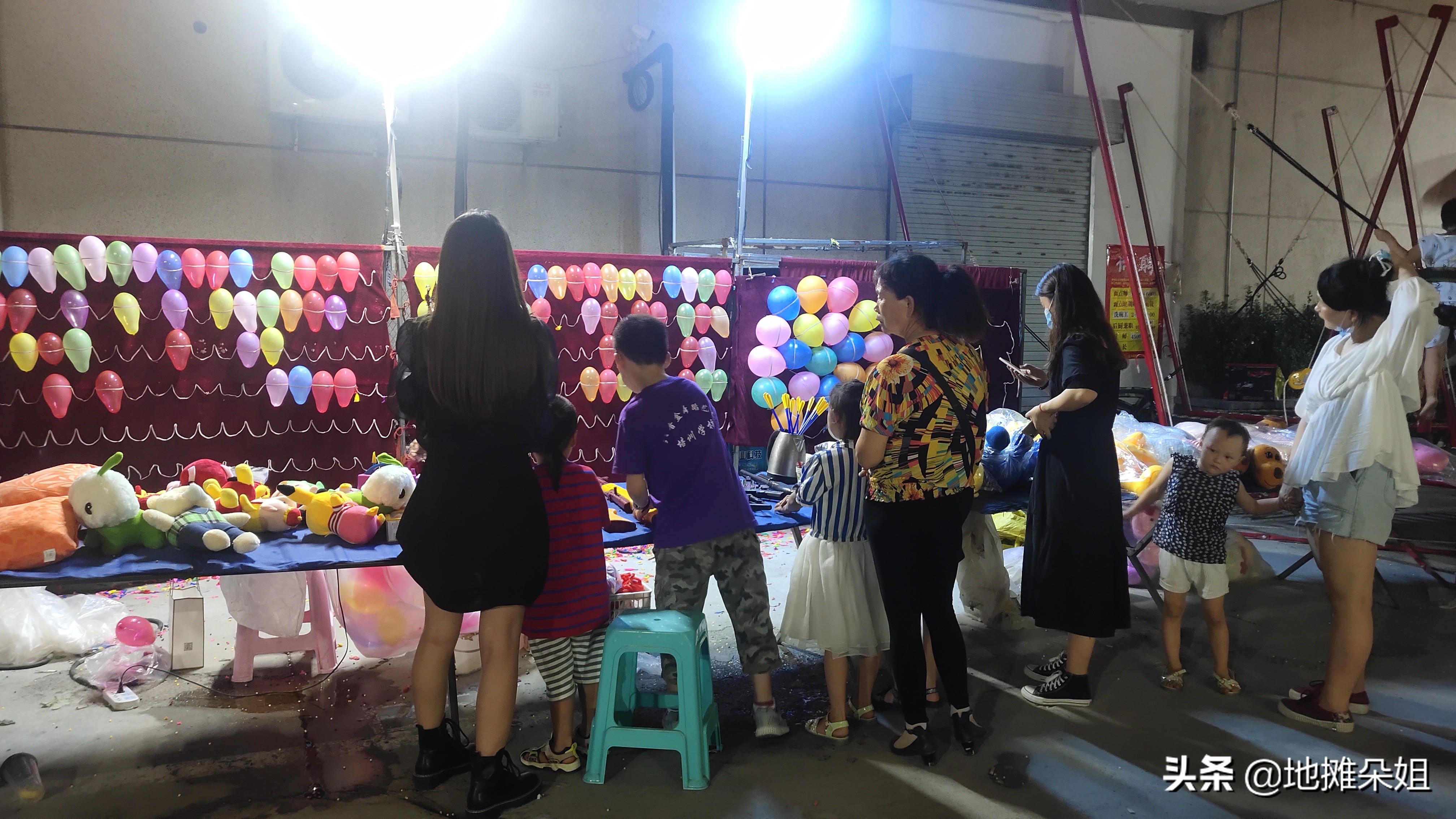 这个摊位真的是太火爆了,好多人都拿着那个塑料枪在那打气球,摊位的