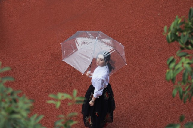 刘诗诗雨中撑伞漫步，白衬衫黑纱裙气质如兰，明目红唇好似画中人