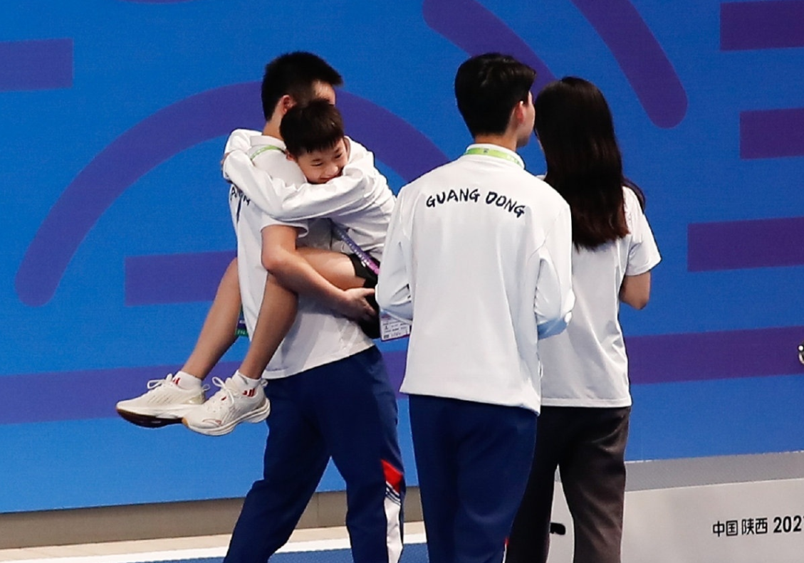 全红婵到教练家做蛋糕，脸伸进模具做鬼脸，教练双手叉腰温柔注视