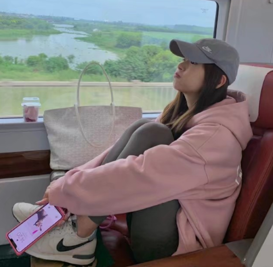 张子萱坐高铁回京看女儿，穿粉色卫衣显少女，为避免争议脚下垫纸