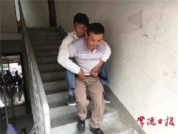 盛忠世背患病老人下楼。记者 游涛 通讯员 谭小军 摄